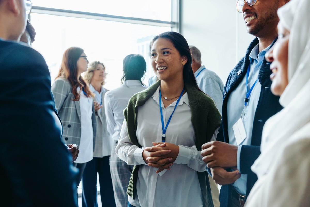 Group of diverse business professionals networking at a conference event, smiling and conversing.