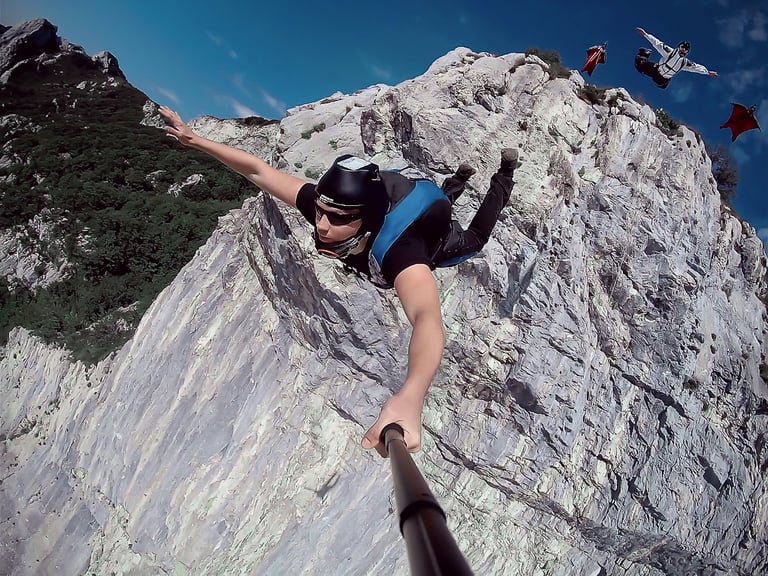 Group of basejumpers jumping from the cliff in Italy