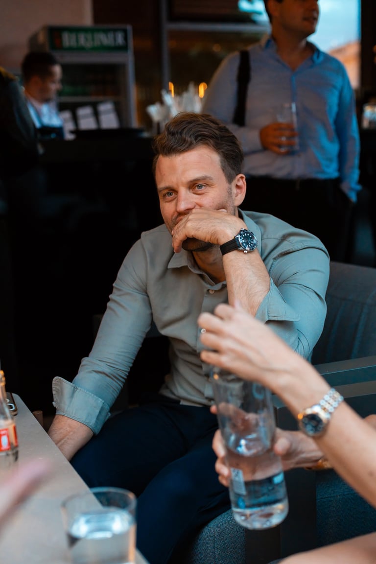 Man in blue shirt sitting at table with hand to face during business meeting or panel event